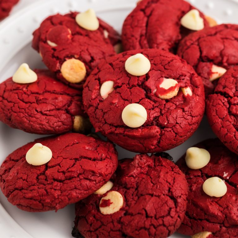 red velvet cake mix cookies with white chocolate chips stacked on a white plate.
