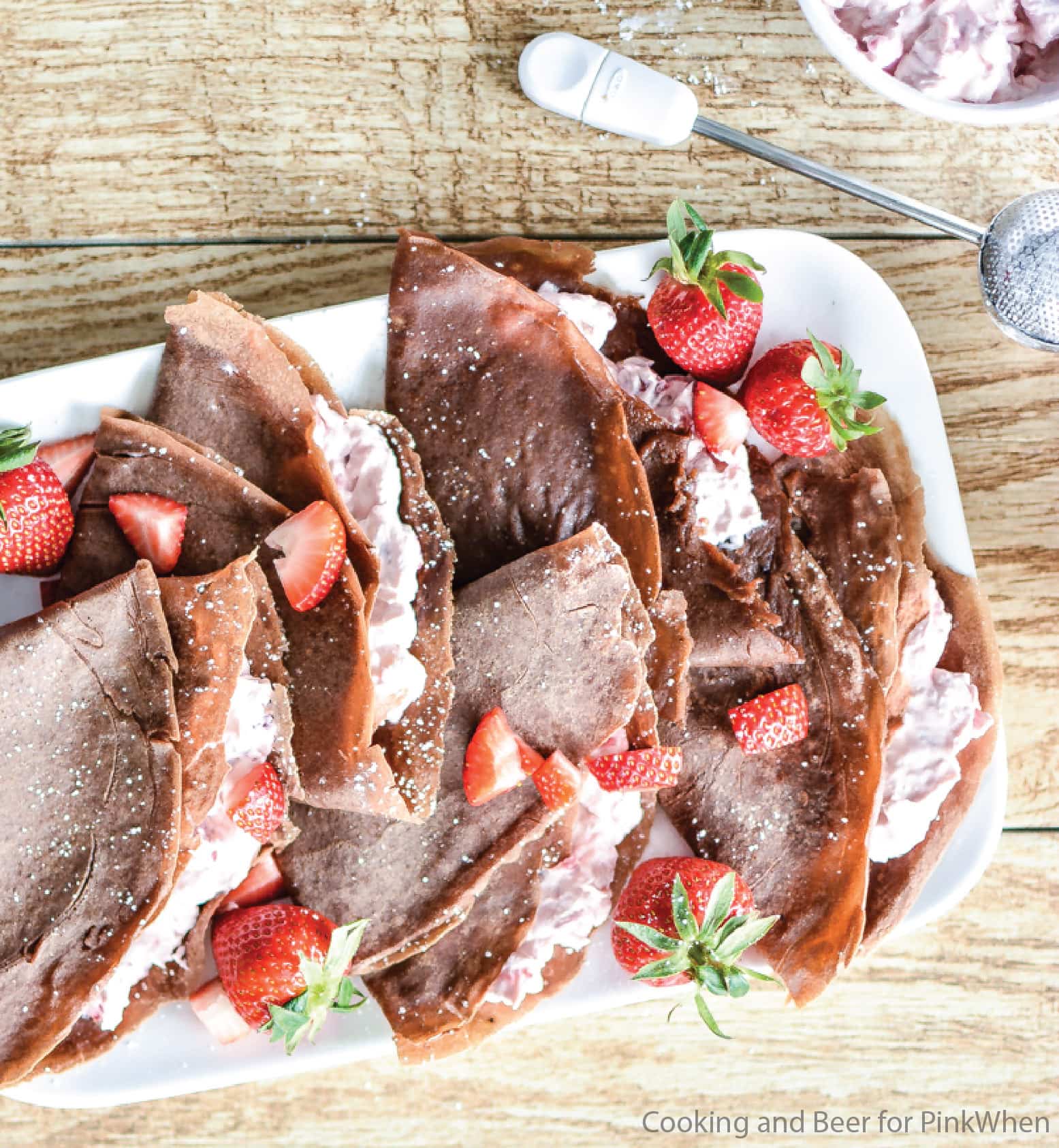 Strawberry Cheesecake Chocolate Crepes on a white plate with fresh strawberries. 
