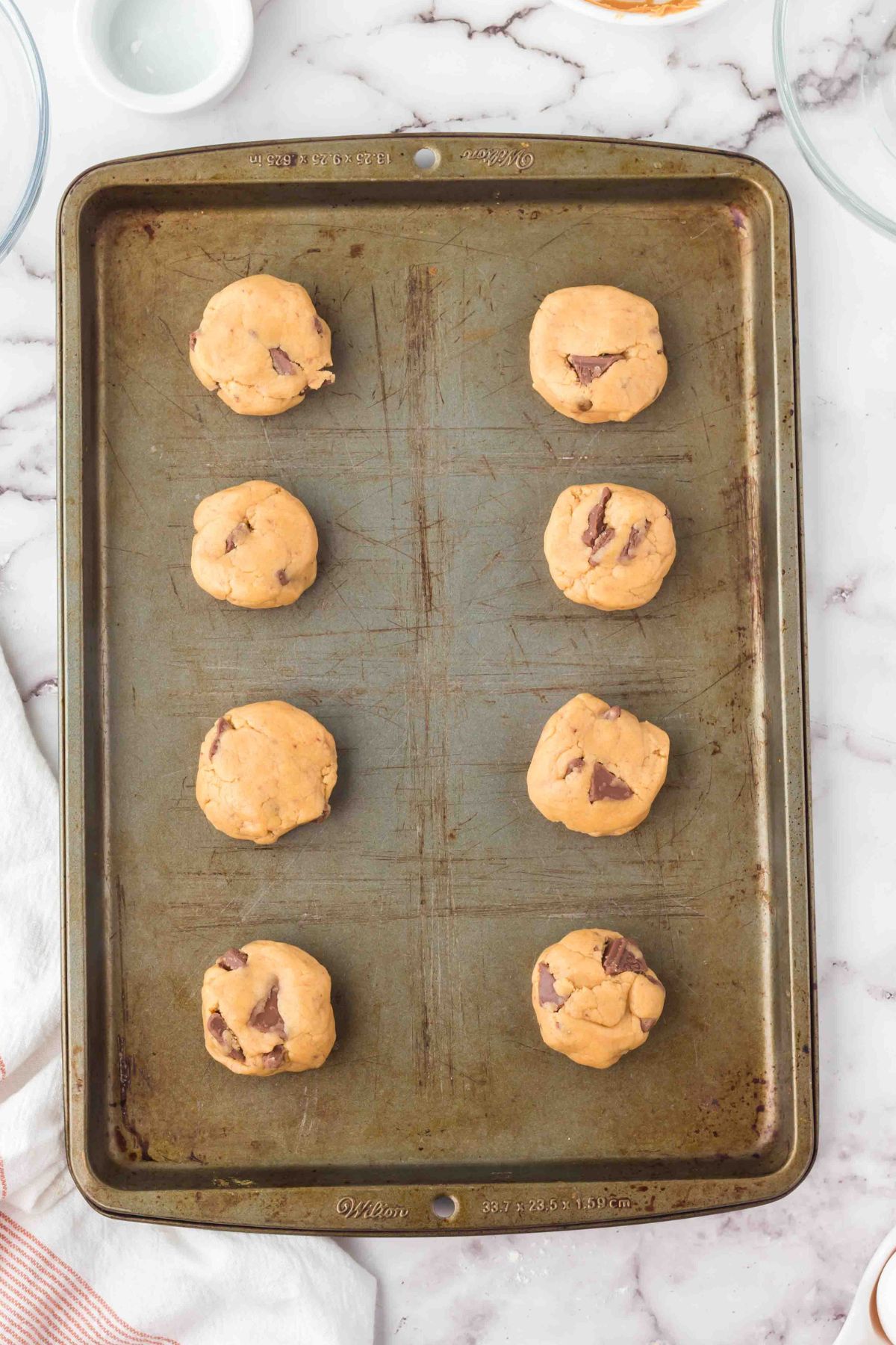 Uncooked cookie dough rolled into balls and placed on a baking sheet. 
