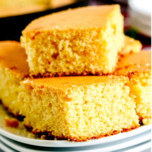 Skillet cornbread cut and stacked on a white plate.