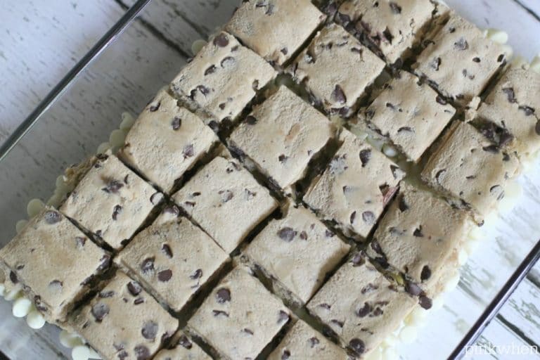 cookie dough squares placed on top of white chocolate chips in a baking dish.