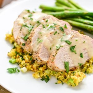 Juicy pork tenderloin sliced over stuffing on a white plate
