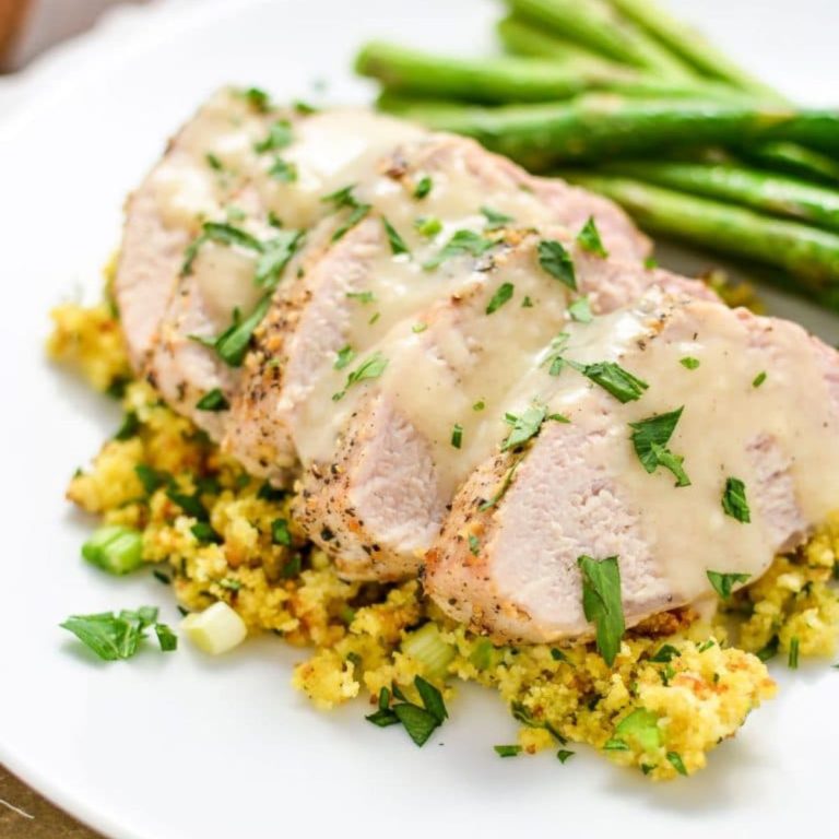 Juicy pork tenderloin sliced over stuffing on a white plate
