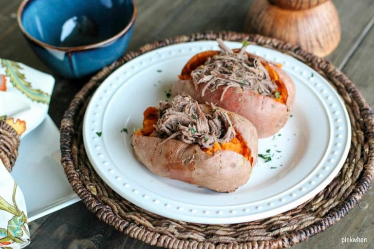 Shredded roast beef on sweet potatoes on white plate and wicker charger