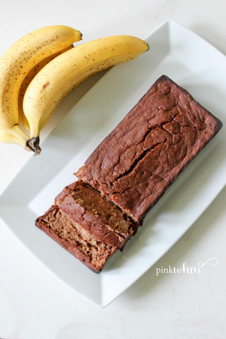 This skinny chocolate banana bread recipe is on a white serving dish next to bananas.