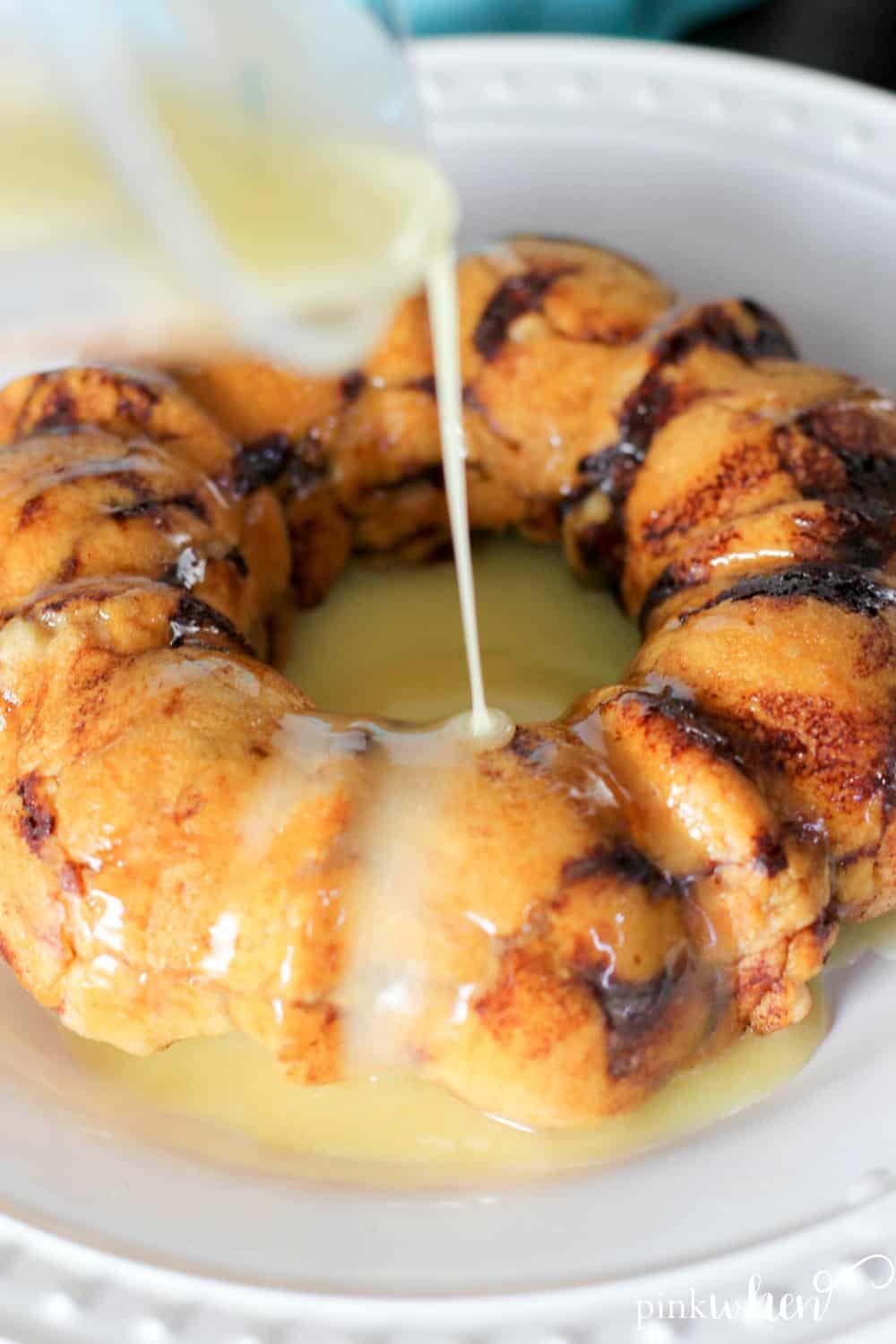 Instant Pot Monkey Bread on a white plate getting a glaze. 