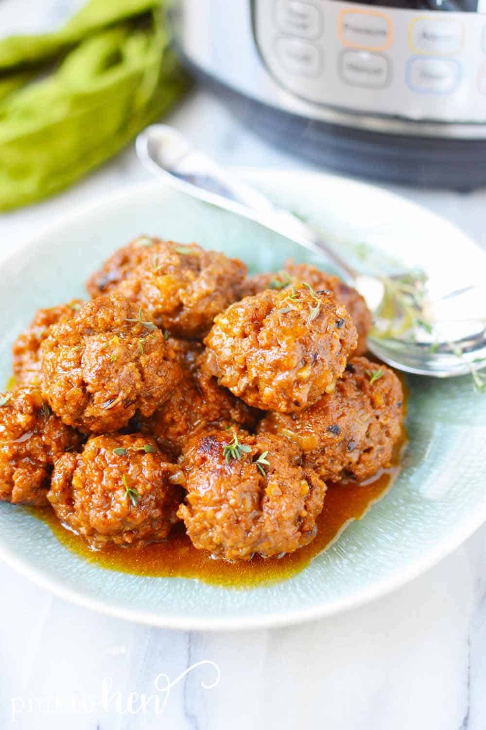 Meatballs on a plate with an Instant Pot in the background. 