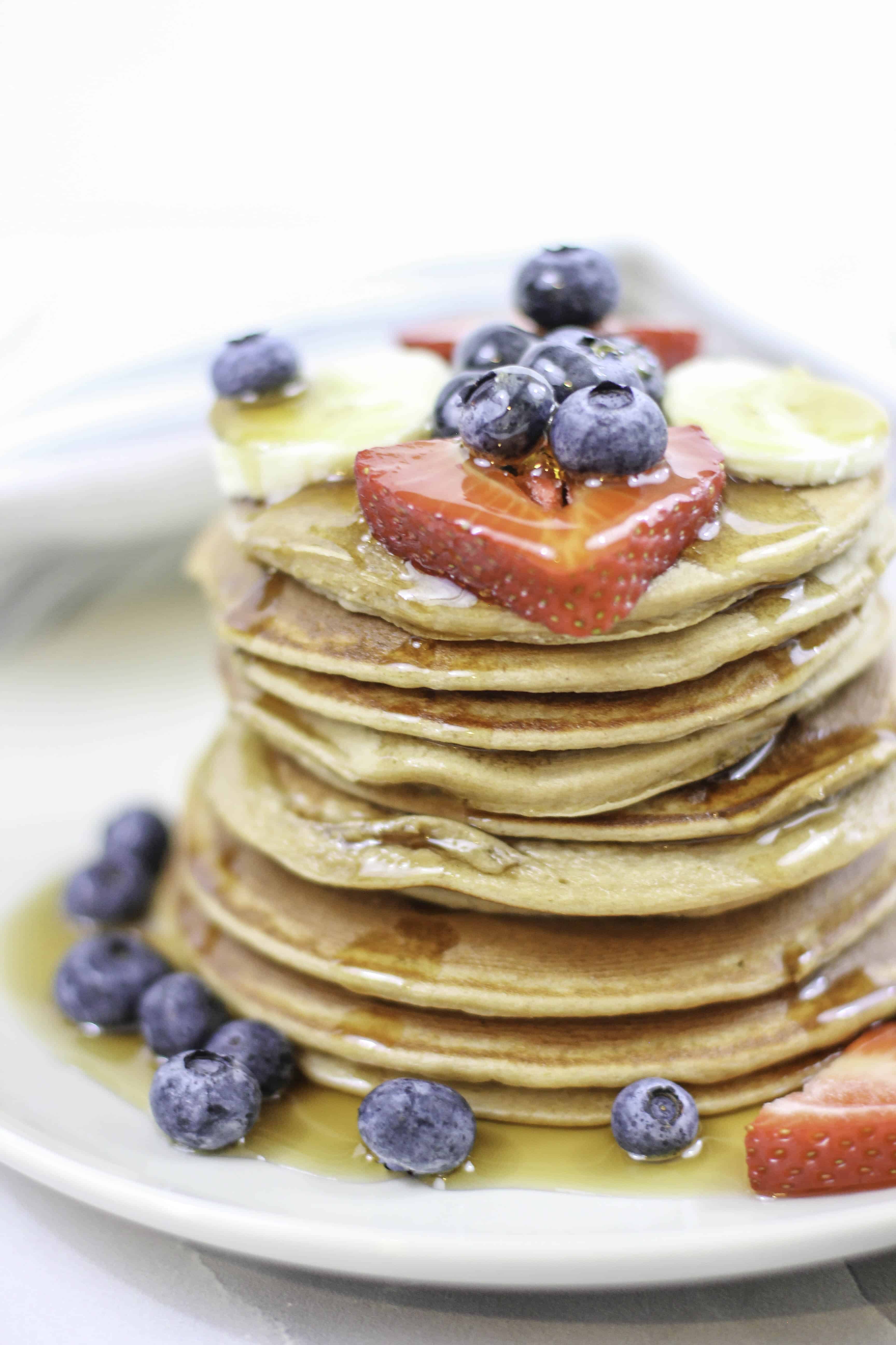 Protein Pancakes covered in fruit and syrup on a white dish. 