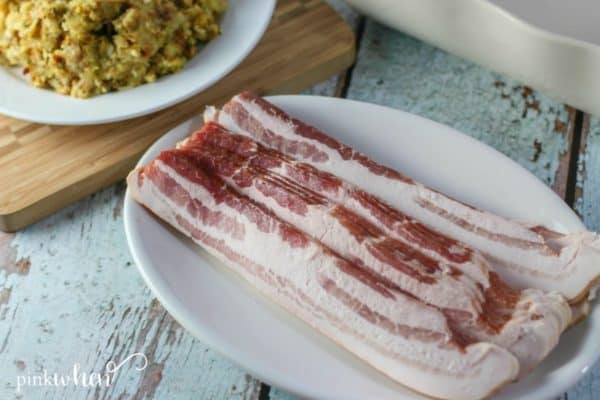 bacon on a white plate and stuffing on a white plate in the background