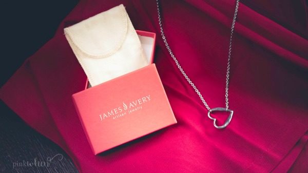 A James Avery Jewelry box with heart necklace on red cloth.
