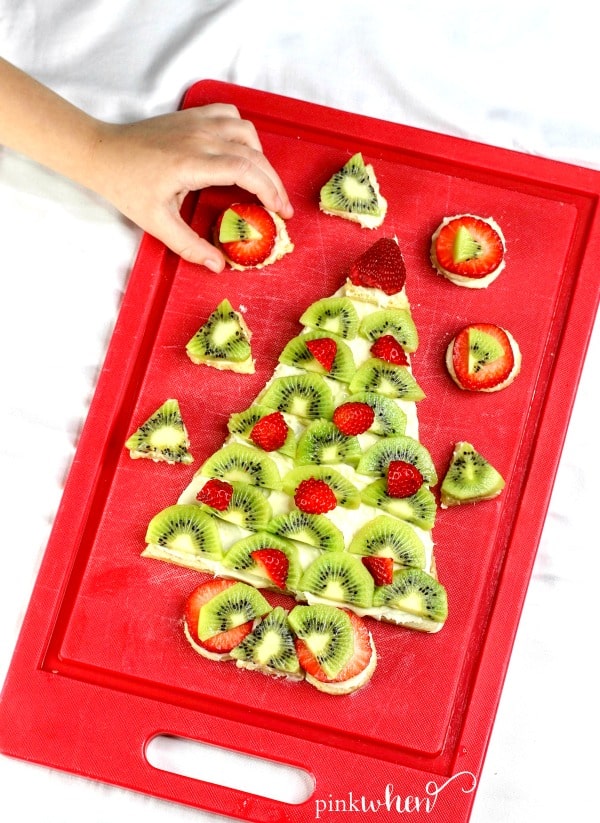 The Ultimate Christmas Fruit Pizza with cream cheese frosting and fresh fruit is what Santa is looking for this Christmas Eve. This easy fruit pizza is a quick and fun recipe and a fun hack for Santa's Cookie Snack! #fruitpizza #ChristmasFruitPizza #ChristmasTreeDessert