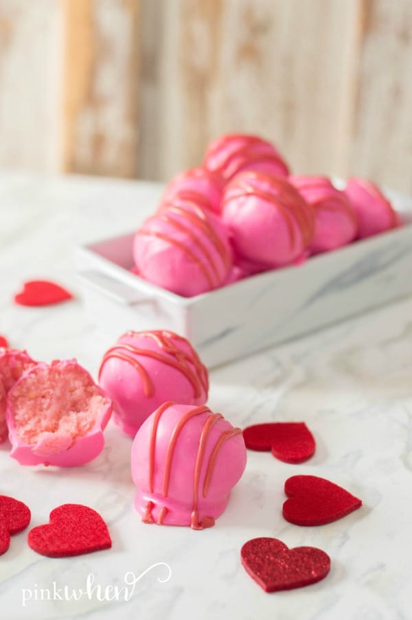 Pink cake balls recipe in tray and on a table.