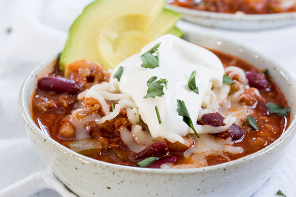 chili topped with sour cream and avocado