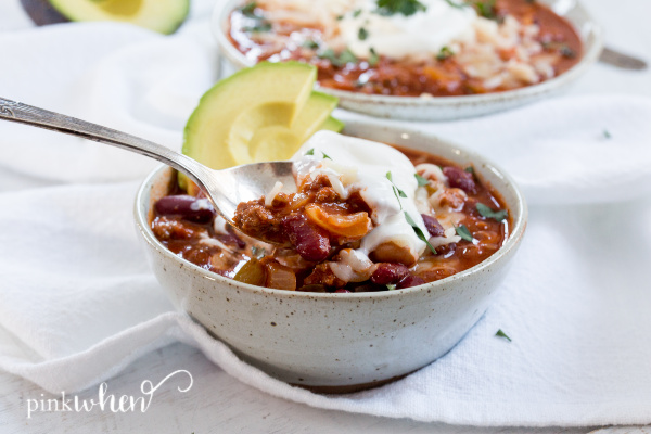Chili with a spoon in a white bowl. 