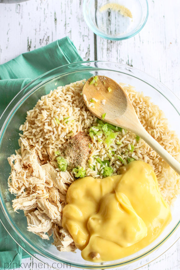 Shredded chicken, rice, sauce, vegetables, and seasoning in a glass mixing bowl.