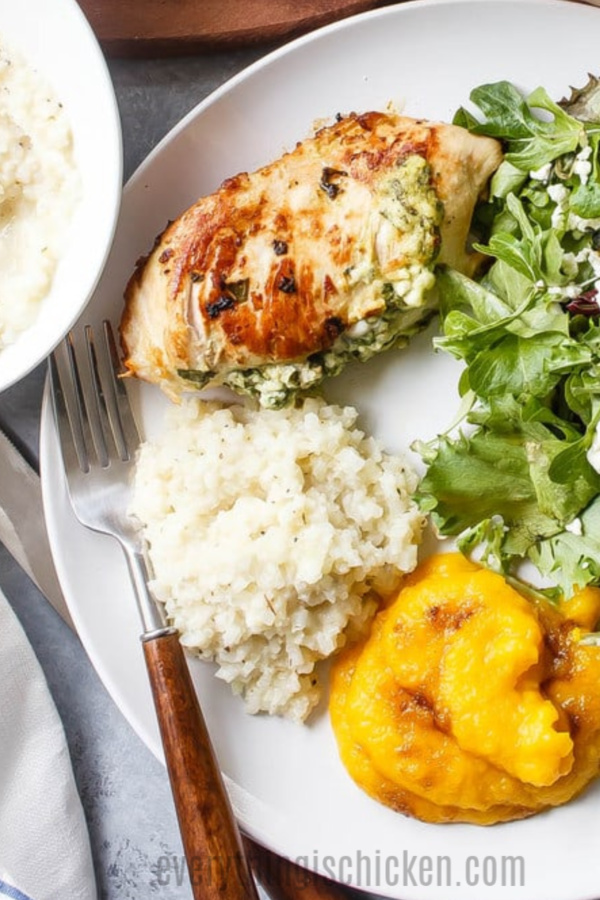 Feta Spinach Stuffed Chicken with sides on a white plate.