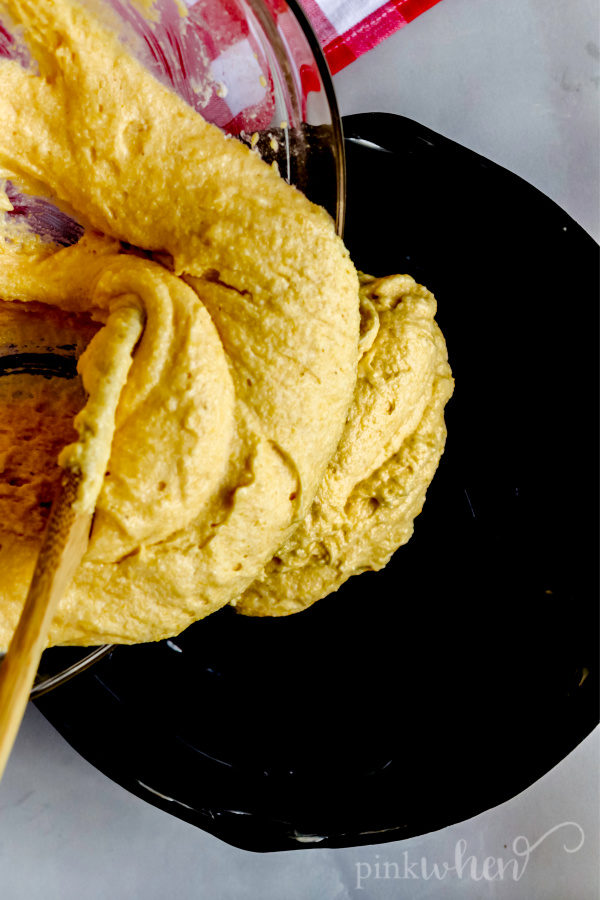 Pouring cornbread batter into a skillet. 