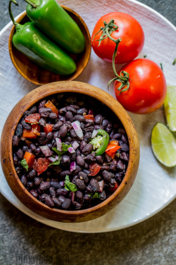 Black beans in a bowl with jalapeno and tomato on a plate. 