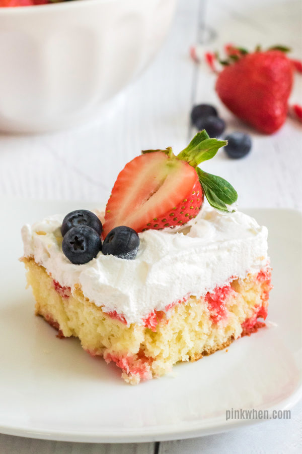 strawberry poke cake on a white plate ready to serve. 