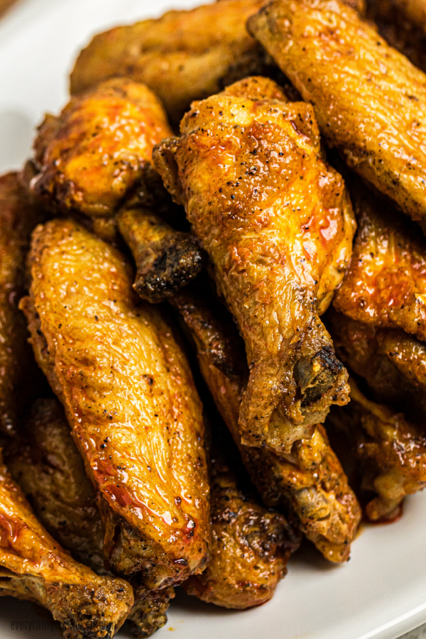 Chicken wings made in an air fryer and stacked on a plate.