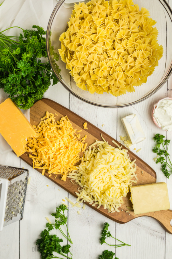 Grated cheese on a cutting board.Noodles in a bowl. 