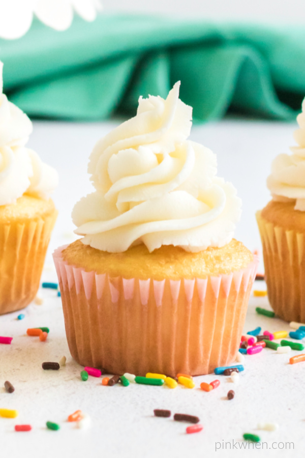Buttercream frosting on a cupcake and surrounded by sprinkles. 