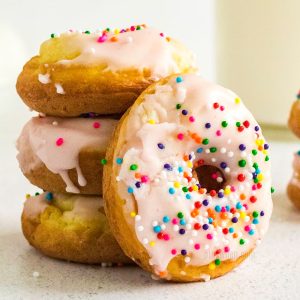 Cake Mix Donuts stacked and covered with icing and sprinkles.