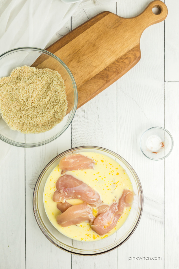 Chicken strips soaking in milk and egg mixture.