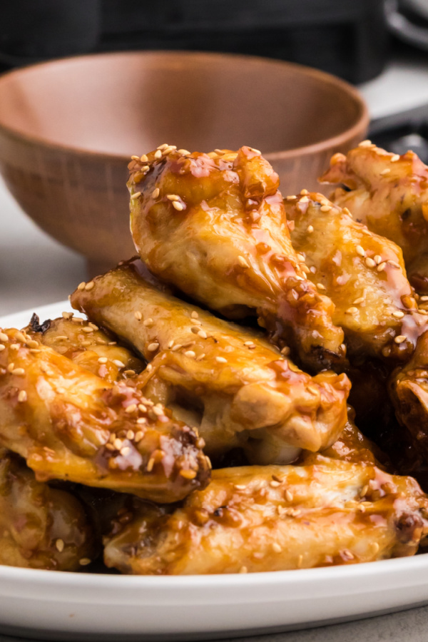 Honey Garlic Wings stacked on a white plate. 