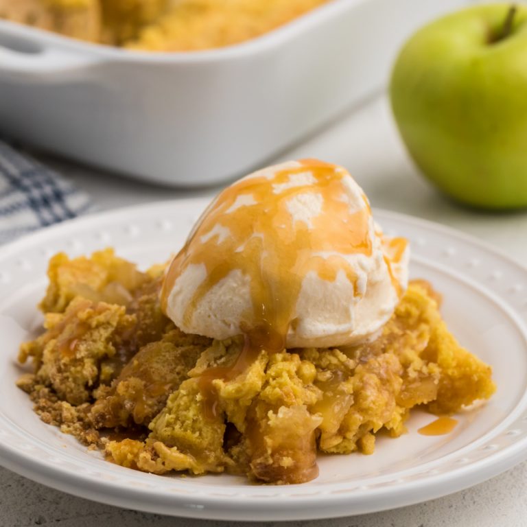 Dump cake with ice cream and caramel sauce on a white plate.