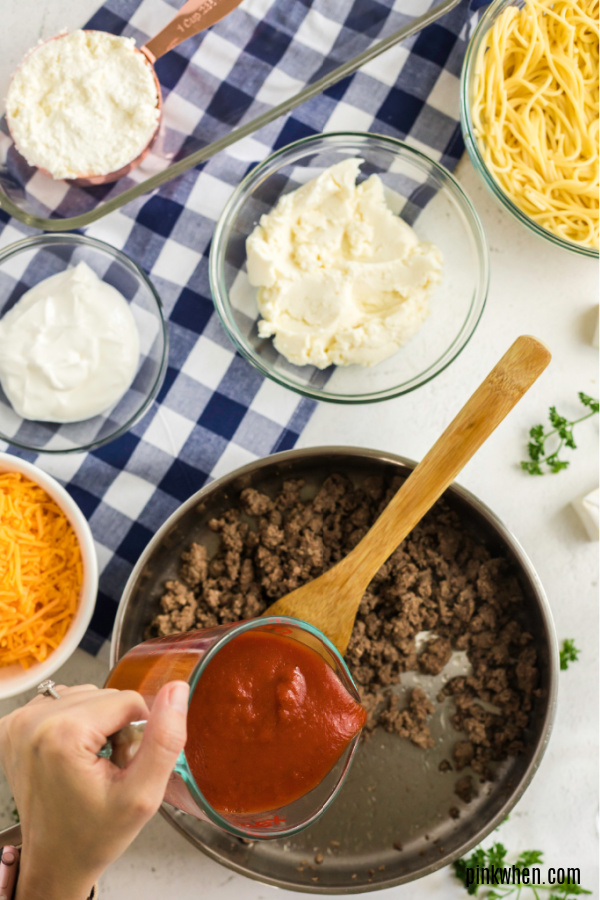 Adding sauce to the meat mixture for baked spaghetti. 