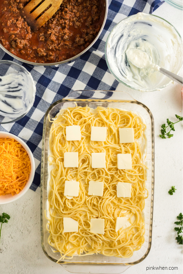 Baked spaghetti layers topped with butter slices. 