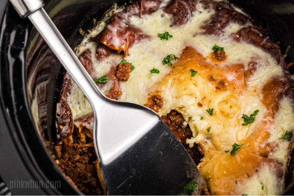 Lasagna in a crockpot with a server. 