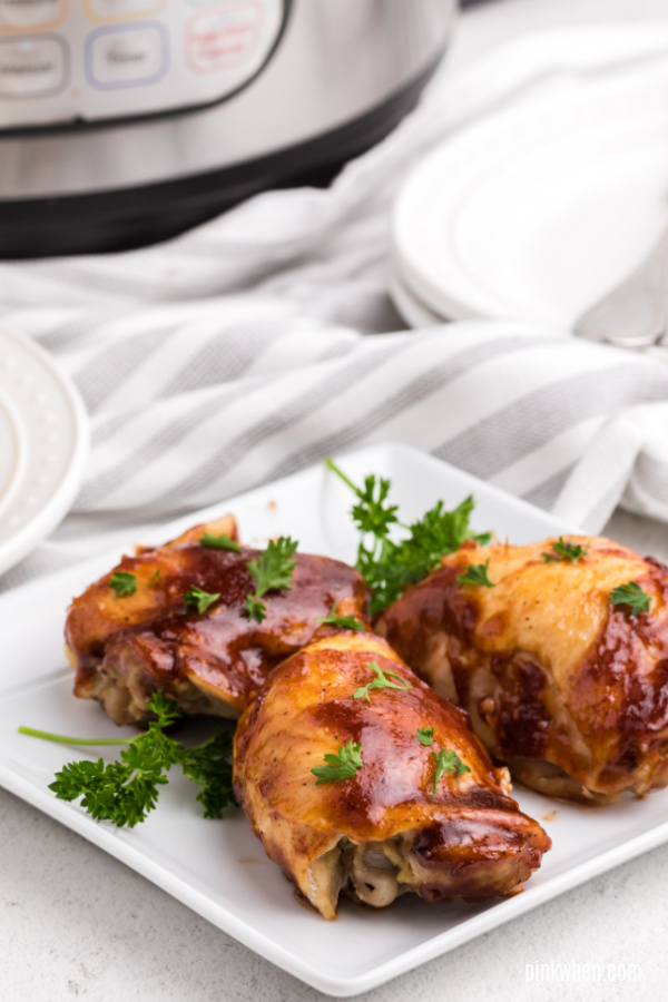 BBQ Chicken thighs garnished with parsley and on a white plate.  
