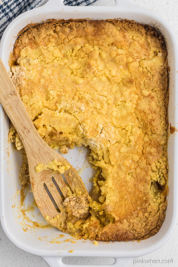 Apple dump cake in a dish with a scoop missing. 