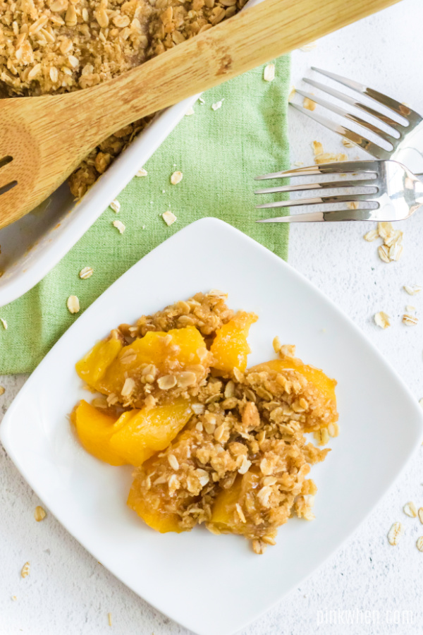 Peach crisp scooped out onto a white plate. 