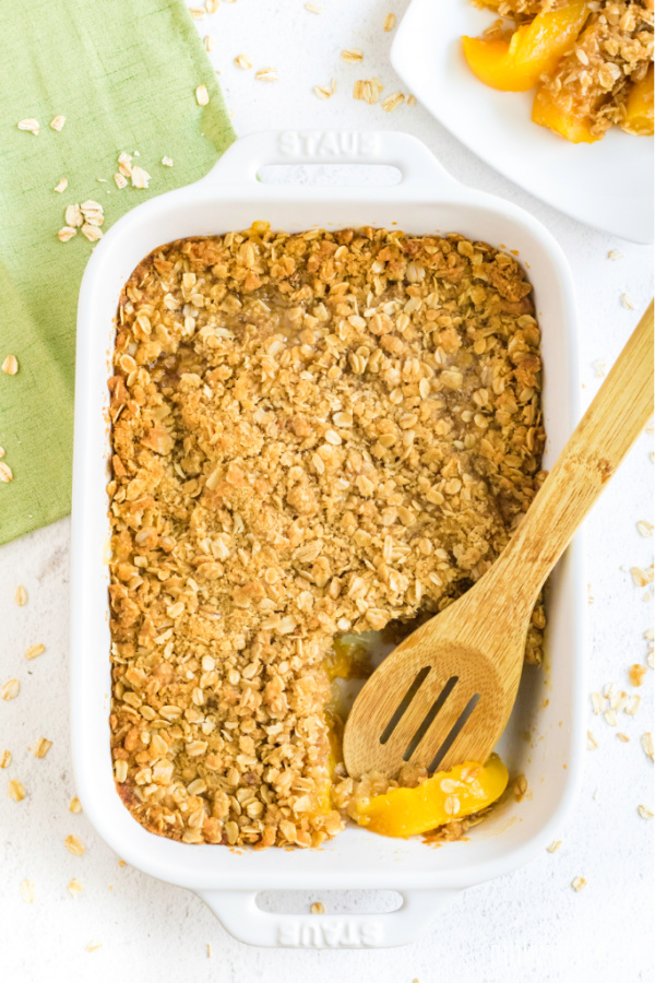 9 x 13 dish with a peach crisp missing a scoop. 