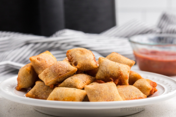 Freshly baked pizza rolls from air fryer on a white plate ready to serve.