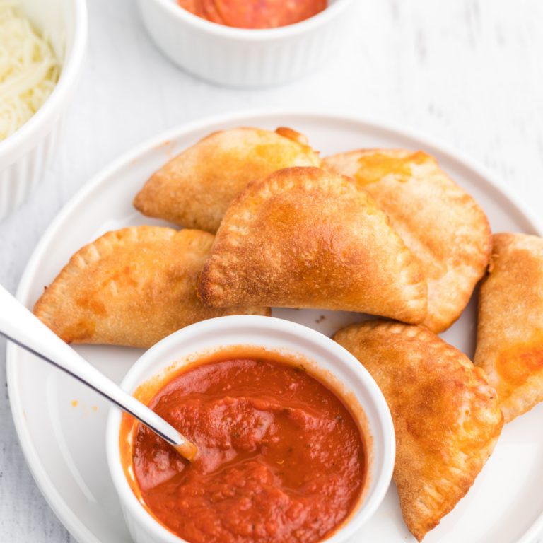 Homemade Air Fryer Pizza Rolls on a white plate with pizza dipping sauce.