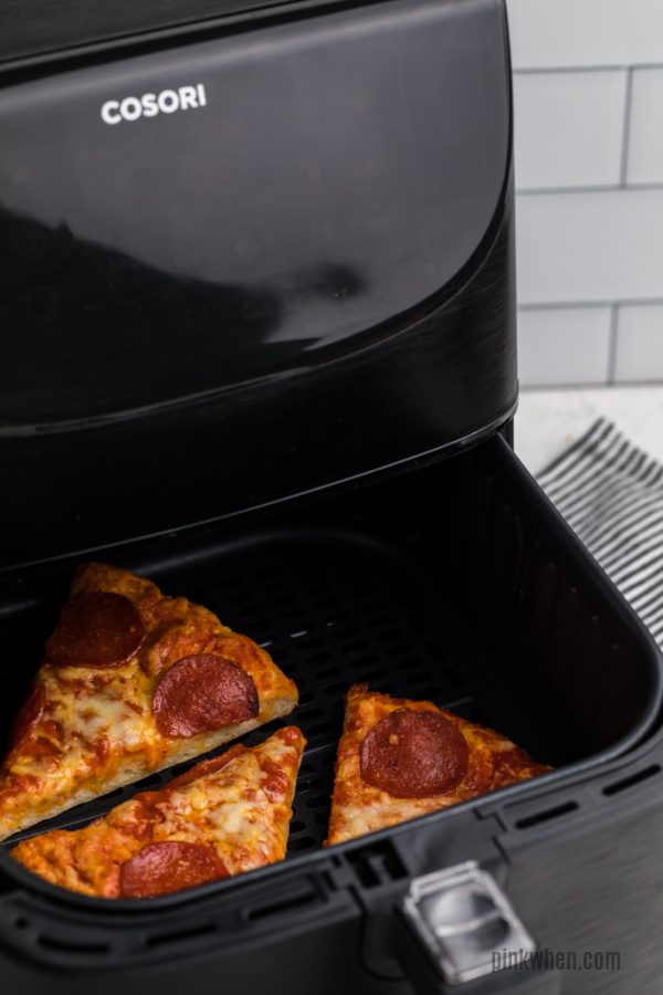 Pizza slices in an air fryer basket ready to be removed. 