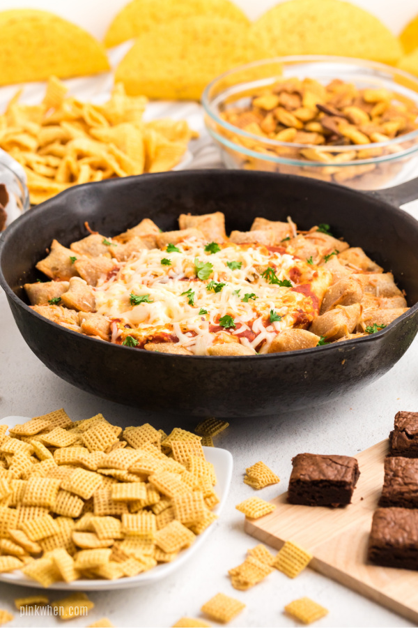 Table spread of snacks with skillet pizza rolls and pizza dip. 