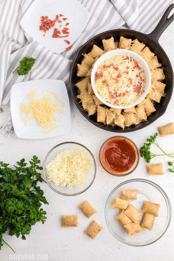 Pizza dip and pizza rolls covered in parmesan cheese and ready to bake.
