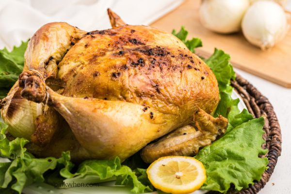Roasted chicken on a bed of luttuce ready to carve and serve.