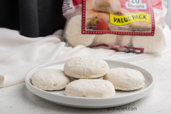 frozen biscuits on a white plate ready to be placed in the air fryer. 