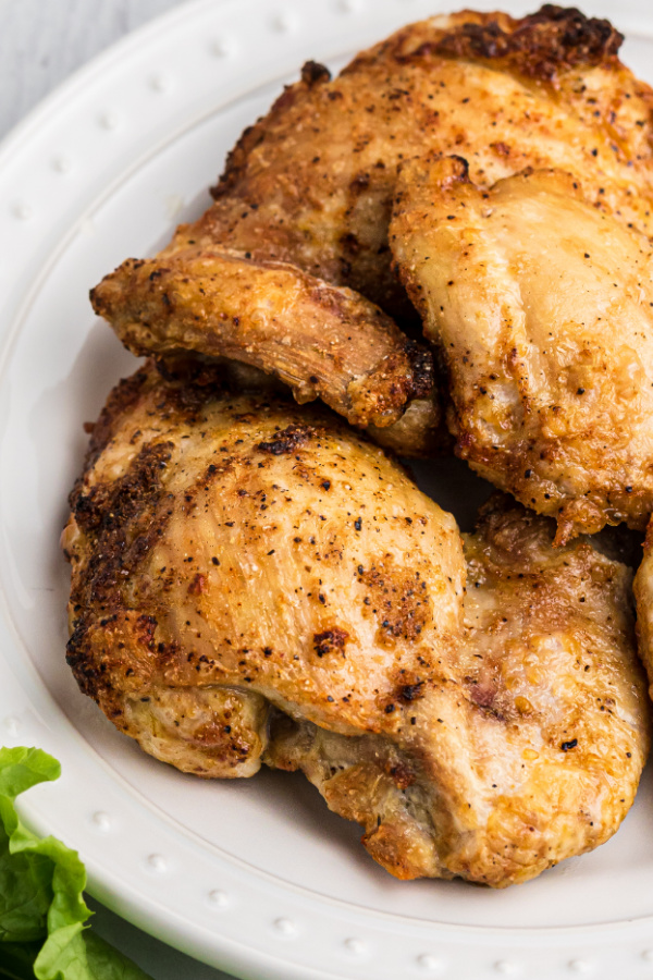Crispy and juicy chicken thighs made in the air fryer and served on a white plate. 