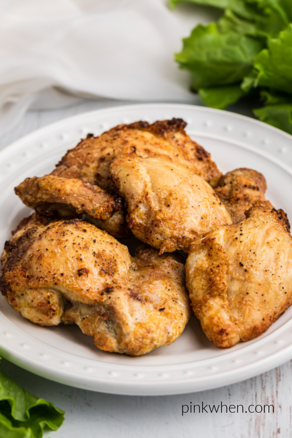 Chicken Thighs seasoned and cooked and on a white plate ready to serve.