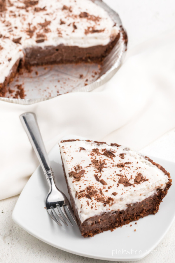 Slice of chocolate cream pie on a white plate ready to eat.