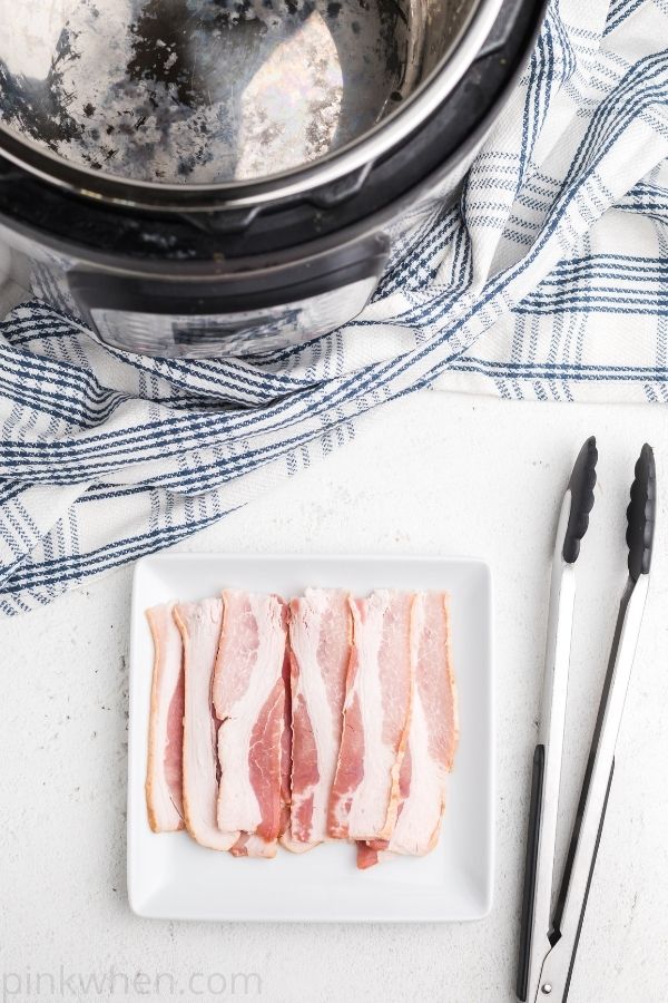 Halved slices of bacon on a white plate. 