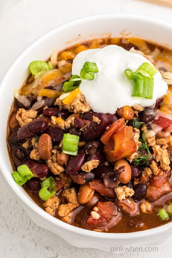 Turkey Chili in a bowl topped with sour cream and green onion tops. 