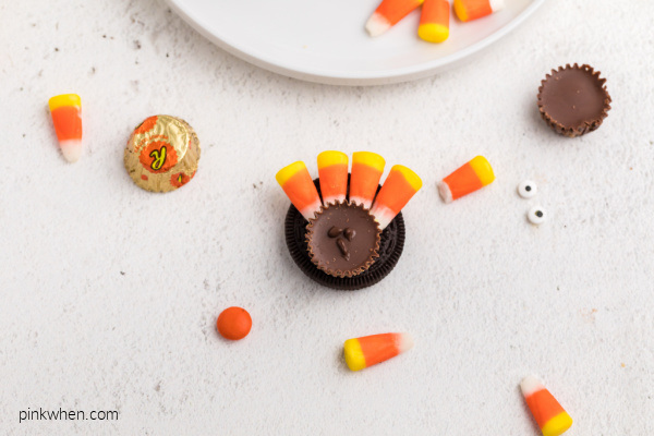 Candy corn and reese's cup on top of an OREO cookie.